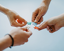 Vier Hände fügen ein Puzzel zusammen