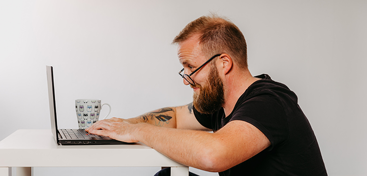 Man looking over the edge of his glasses at his laptop 