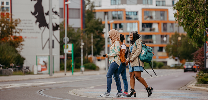 three young women walking across the campus